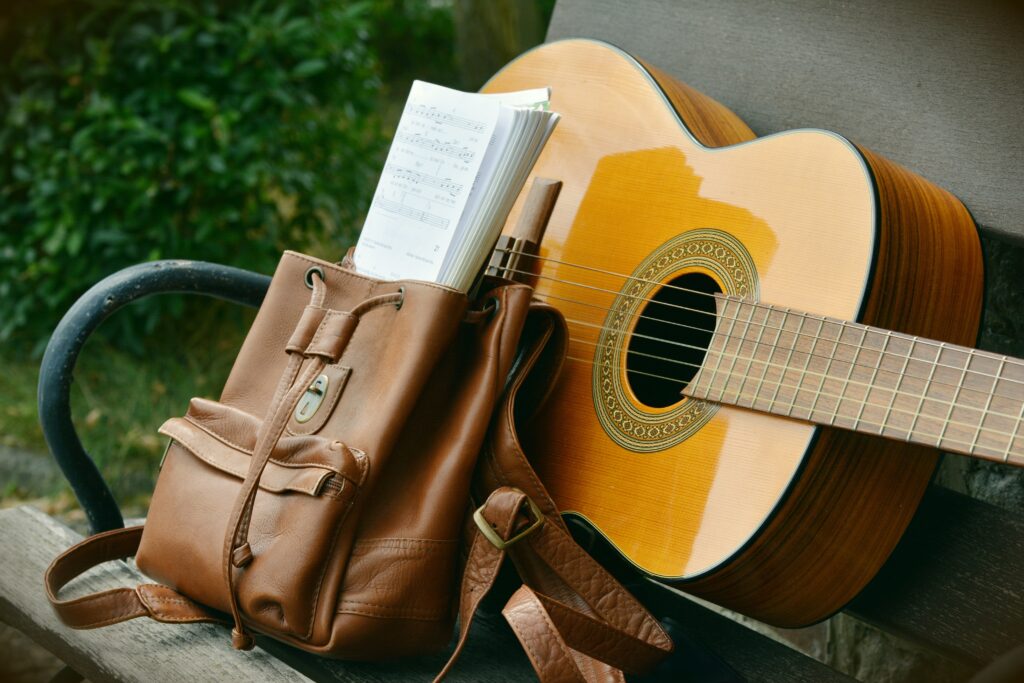 guitar with bag and music on a bench